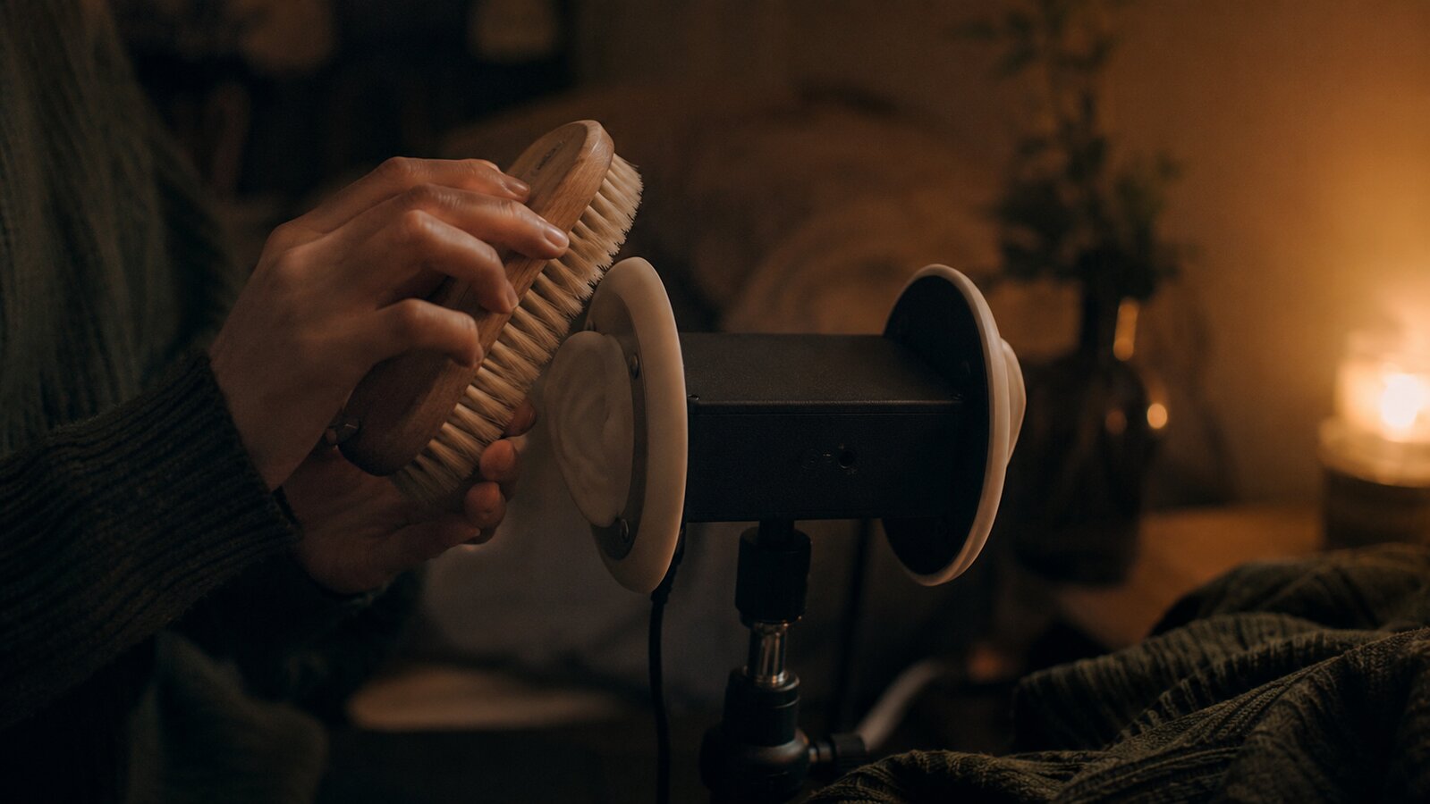 Hands tapping a wooden brush beside a binaural ASMR microphone