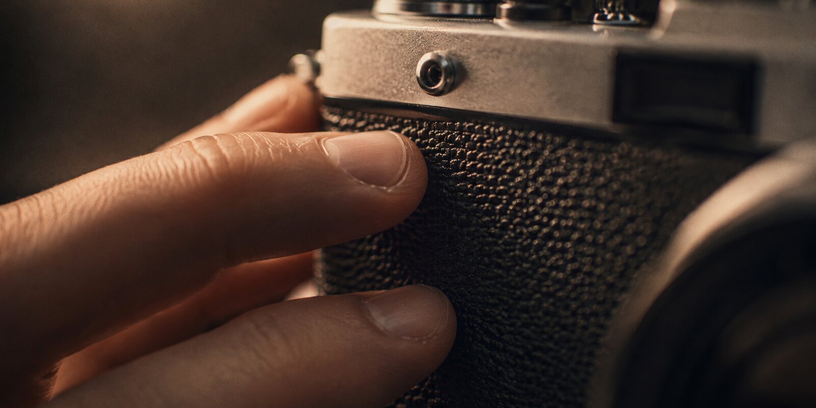 Fingertips tapping the textured grip of a vintage camera body — ASMR trigger