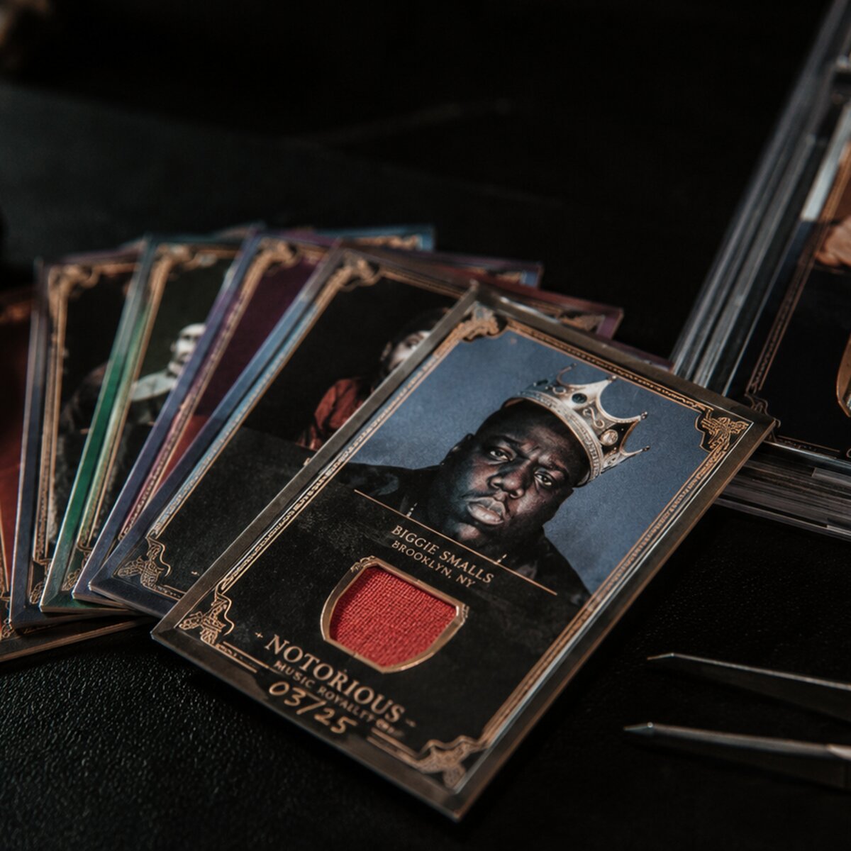Collectible band trading cards fanned out with a magnifier and tweezers