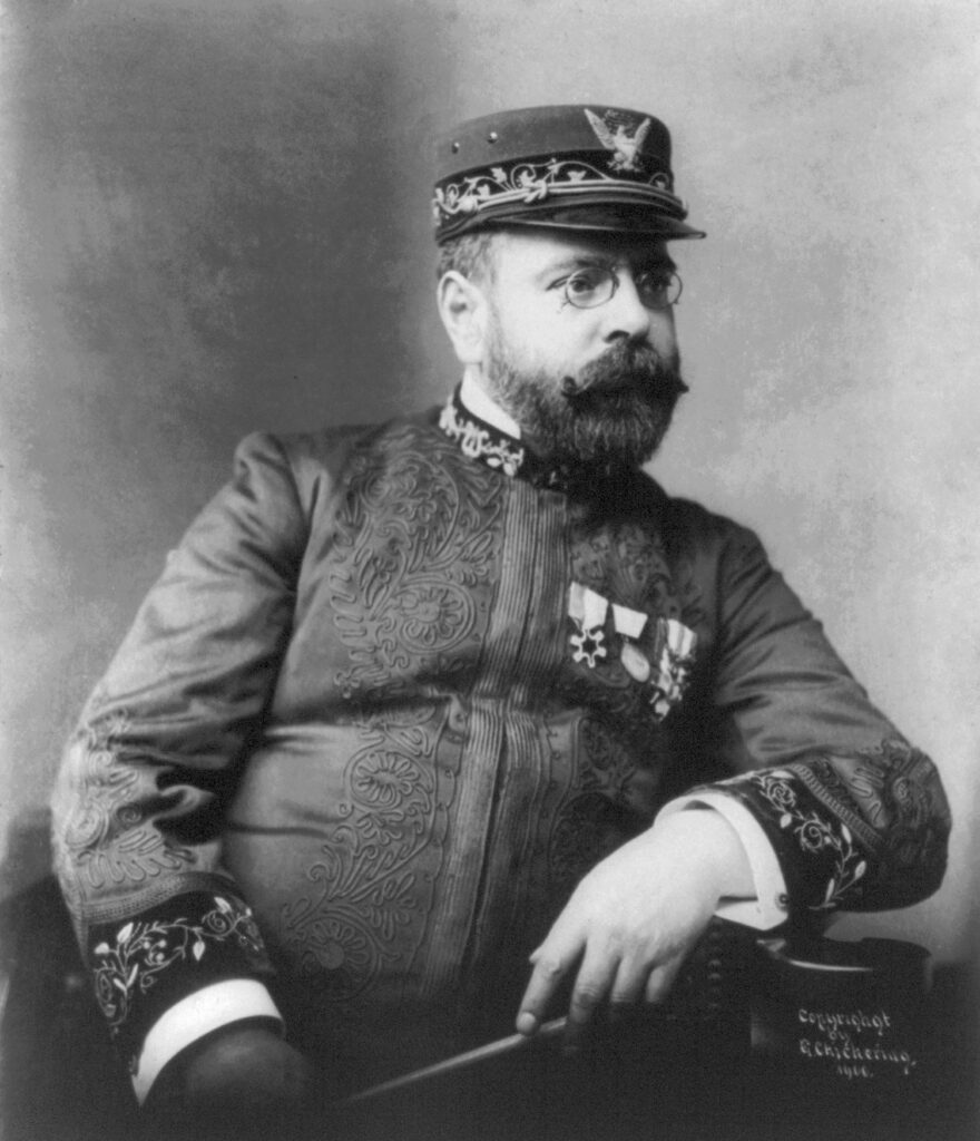 Formal portrait photograph of John Philip Sousa c. 1900 — bearded, in a dark suit, looking slightly off-camera, soft studio lighting and period photographic tones