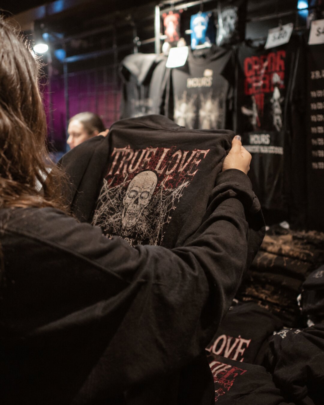 Fan picking a hoodie at the merch table after a show